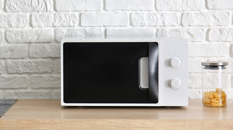 A microwave on a counter next to some pasta