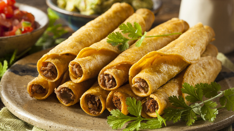 Platter of meat-filled taquitos garnished with cilantro