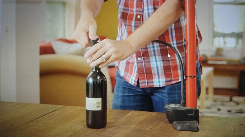 Man placing needle of bike pump into wine opening with cork