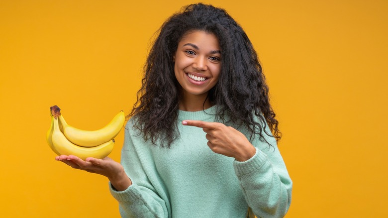 girl holding up banana bunch