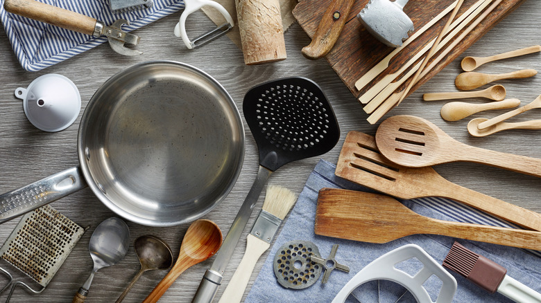 Collection of cooking utensils and tools sitting on a table.