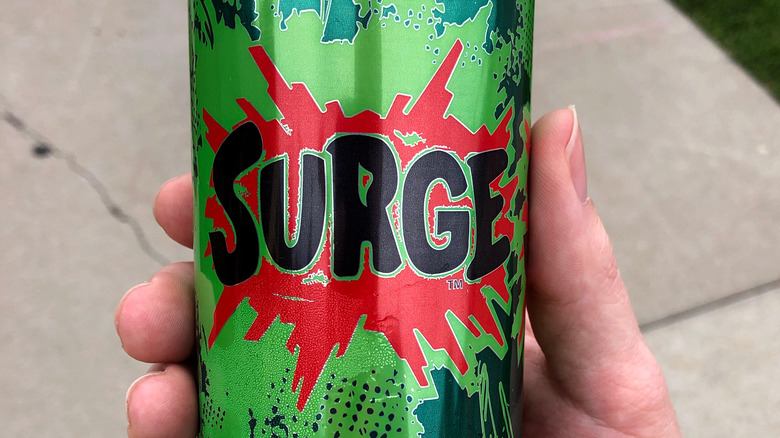 Hand holding a can of Surge