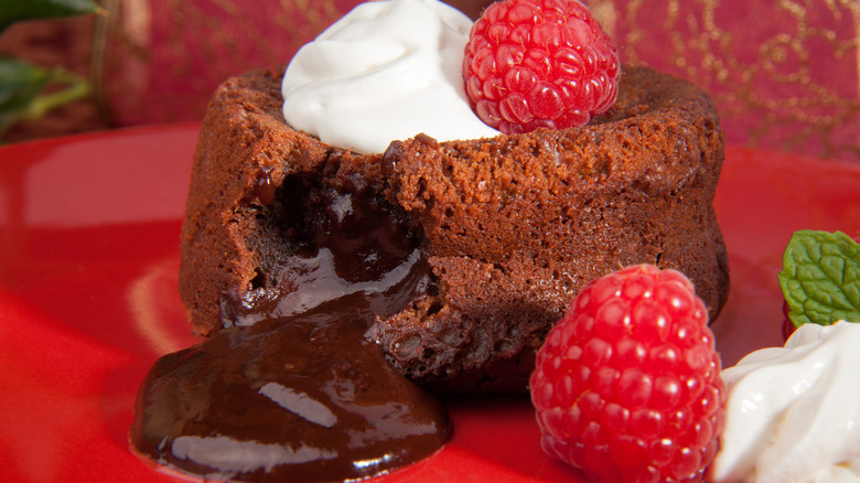 A chocolate lava cake with whipped cream and raspberries