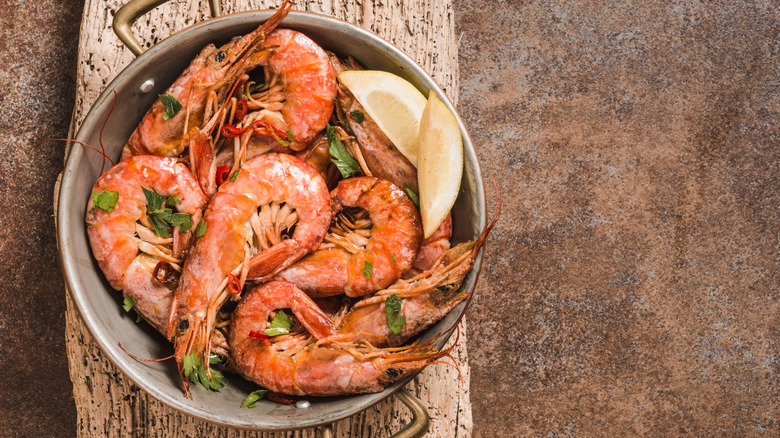 A pot of bright red shrimp on a wood plank