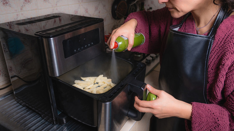 Home cook sprays cooking spray into her air fryer