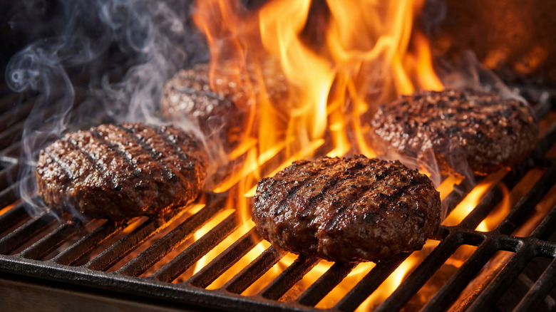 Burger patties on flaming grill