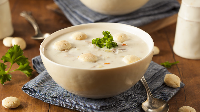 Bowl of clam chowder with crackers on blue napkin