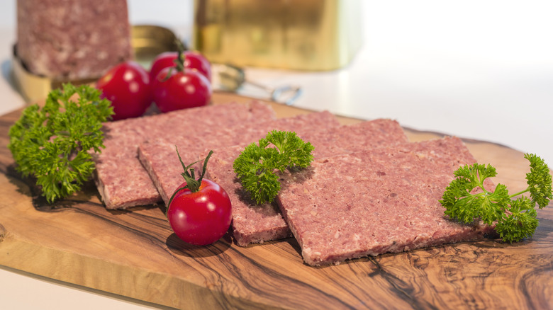 Corned beef on cutting board with tomatoes and parsley
