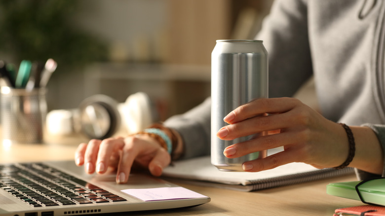 Person at laptop drinking from a can
