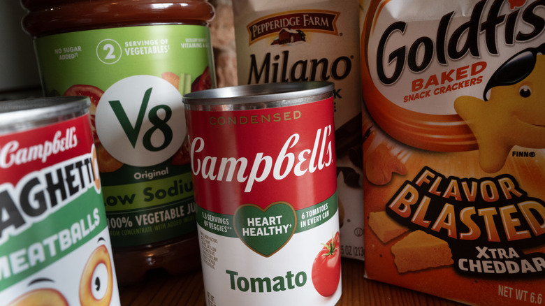 A can of Campbell's soup surrounded by Campbell's family products: V8, Goldfish, Milano cookies