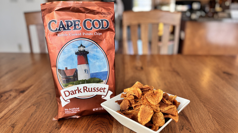 dark russet potato chips in bowl next to chip bag