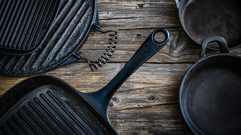 An assortment of cast iron cookware on wood table