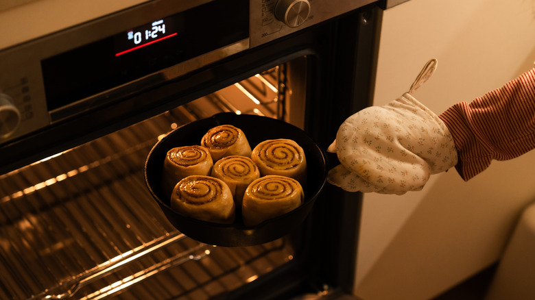 Taking a cast iron skillet with cinnamon rolls out of the oven