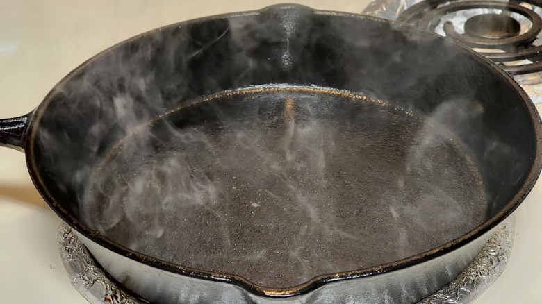 cast iron skillet being seasoned on stove