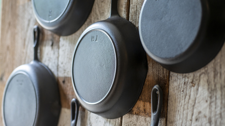 cast iron skillets hanging on a wooden wall