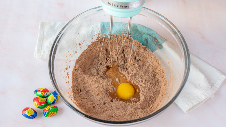 adding egg into dry Cadbury Creme Eggs cupcakes ingredients