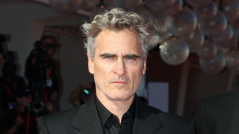 Actor Joaquin Phoenix poses seriously in a black suit