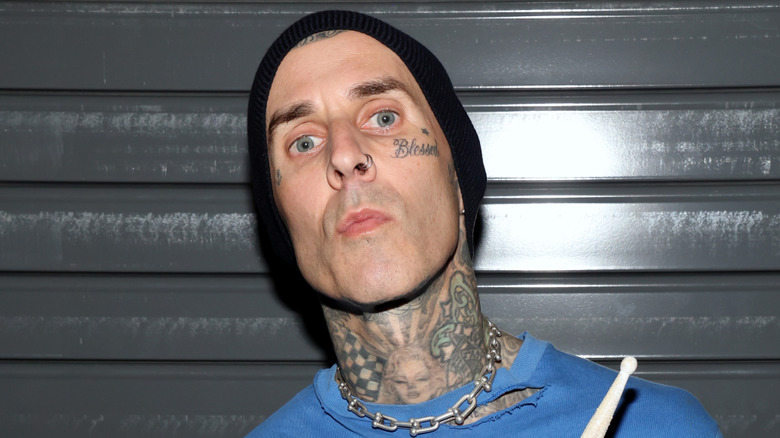 Travis Barker poses in front of grey wall