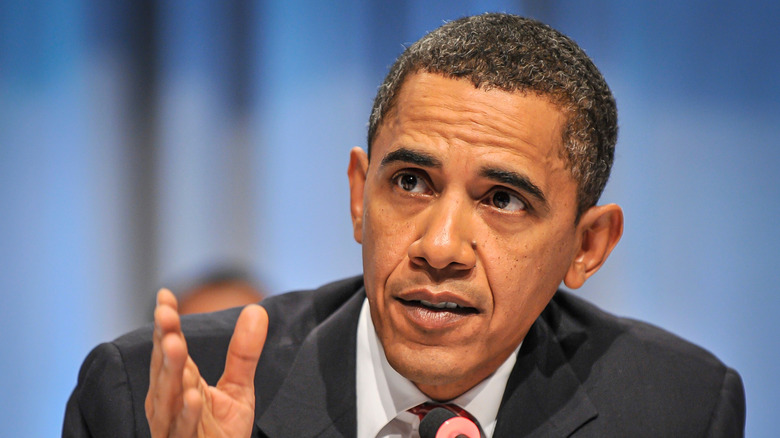 Barack Obama wearing a suit and gesturing with his hand