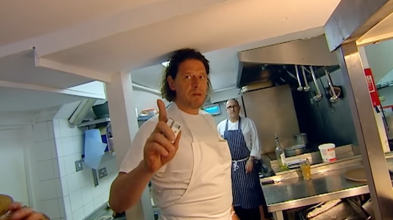 Marco Pierre White glaring and gesturing beyond the camera on an episode of "Marco's Great British Feast"