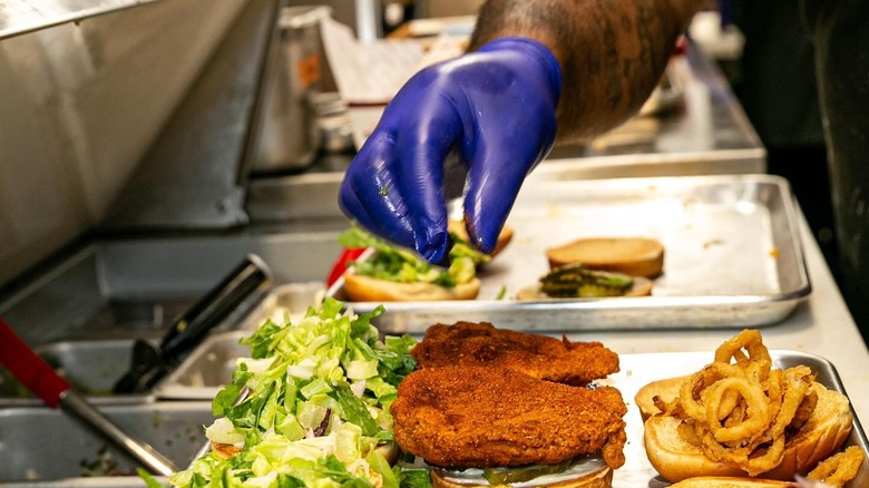 man making fried chicken sandwiches
