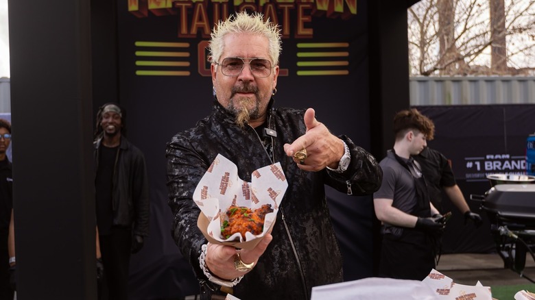 Guy Fieri holding chicken wings