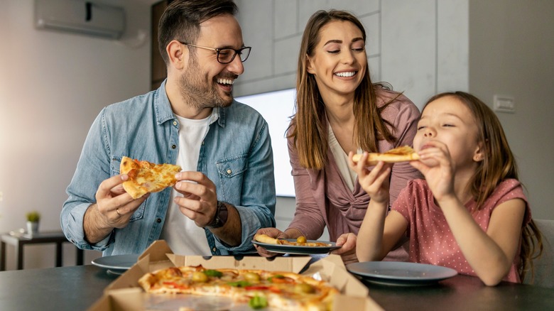 man eating pizza eyes closed