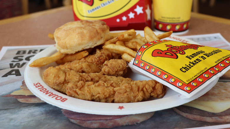 A plate with Bojangles chicken tenders, a biscuit, and fries