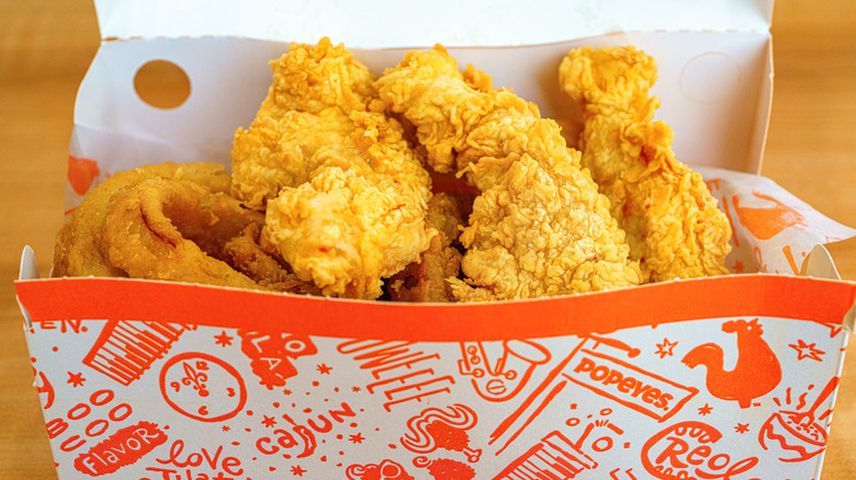 Closeup of an open takeout box of Popeye's chicken tenders