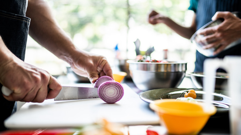 Chef cutting red onion in commercial kitchen