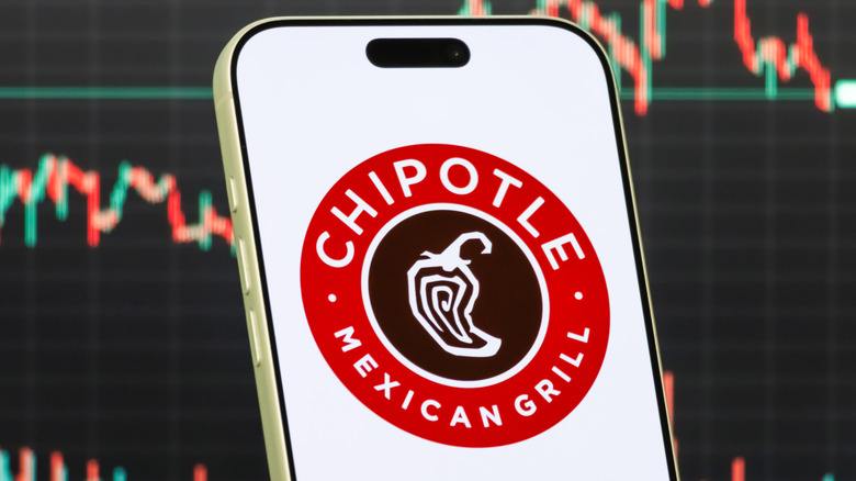 Smartphone with Chipotle logo over a computer screen