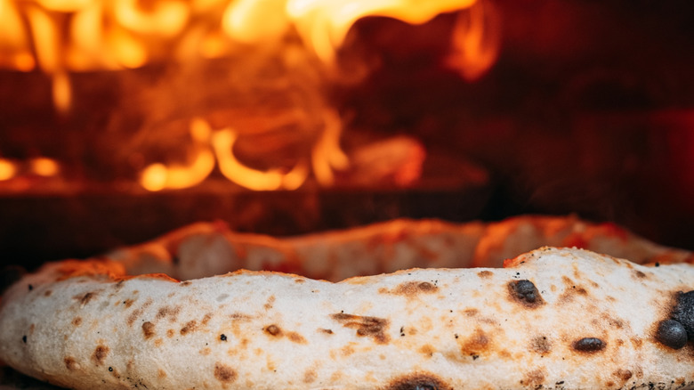 Pizza being put in a wood-fired oven