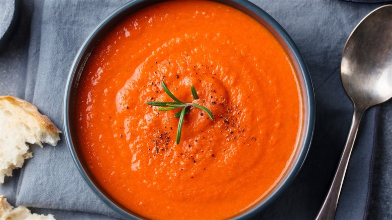 tomato soup in a dark grey bowl served with crusty bread