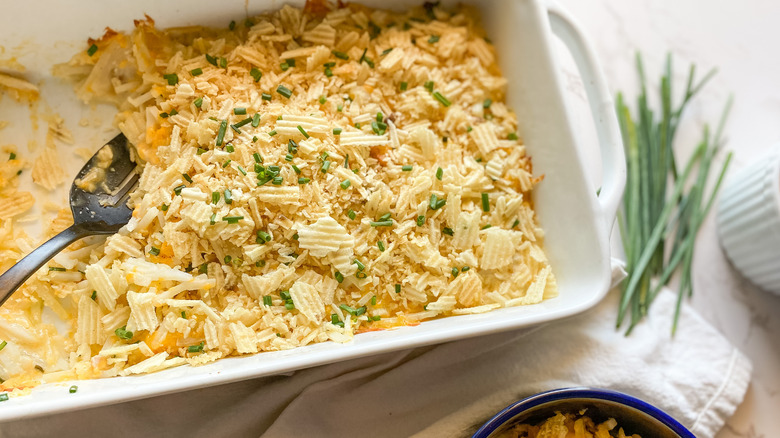 cheesy potato casserole in baking dish with spoon