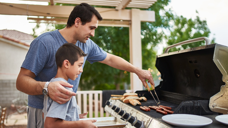 Person and child grilling hot dogs