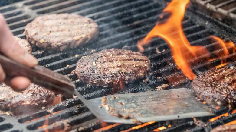 Person flipping burgers on a grill