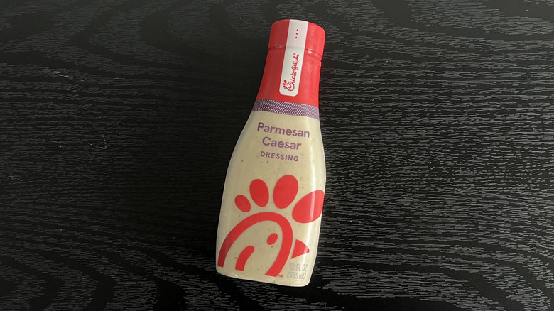 Bottle of Chick-fil-A Parmesan Caesar salad dressing laying down on black table