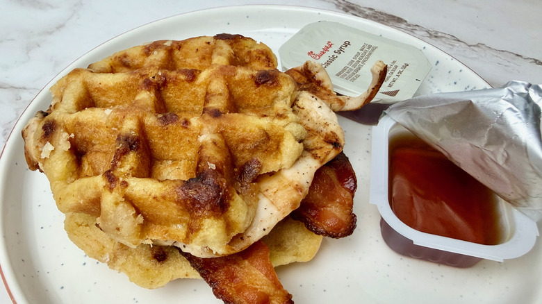 A Chicken & Waffles Breakfast Sandwich with Grilled Filet and syrup from Chick-fil-A