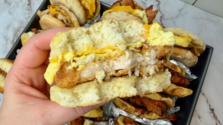 Hand holding a Chick-fil-A Chicken, Egg & Cheese Biscuit with bites taken out