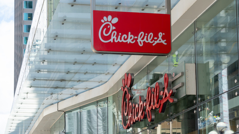 Chick-fil-A signage outside of larger office-type building during daytime.