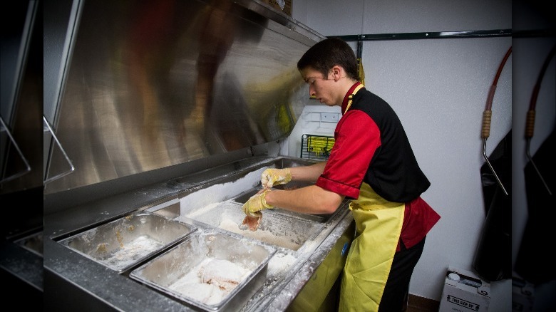 A Chick-fil-A employee breading chicken