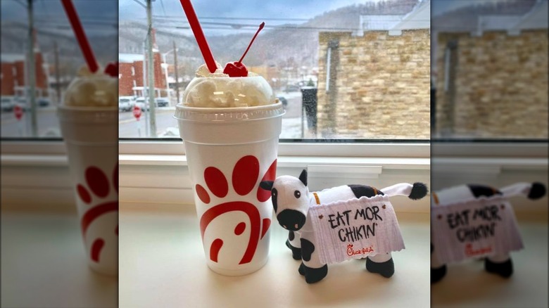 A Chick-fil-a milkshake next to a cow plush toy.