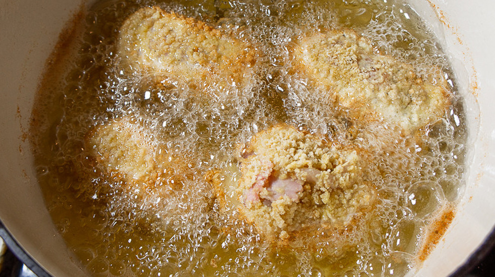 una pentola di olio bollente con dentro il pollo fritto