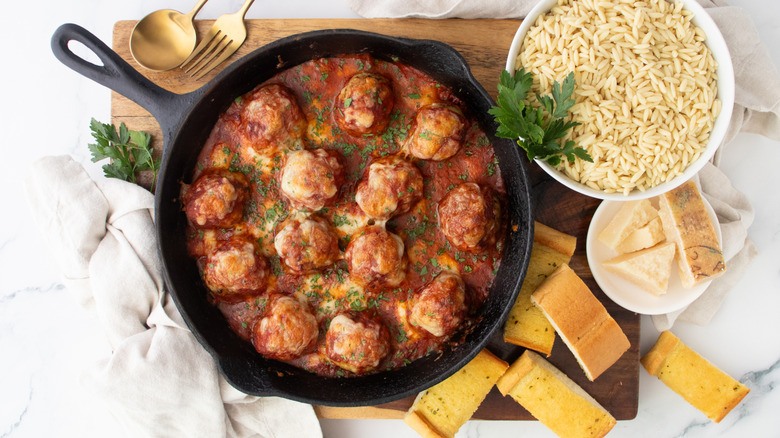 Chicken parmesan meatball skillet next to rice and garlic bread