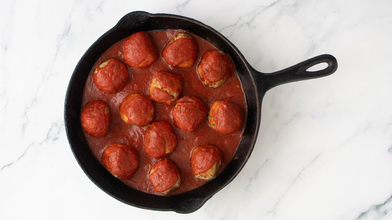 Meatballs coated in pizza sauce in skillet
