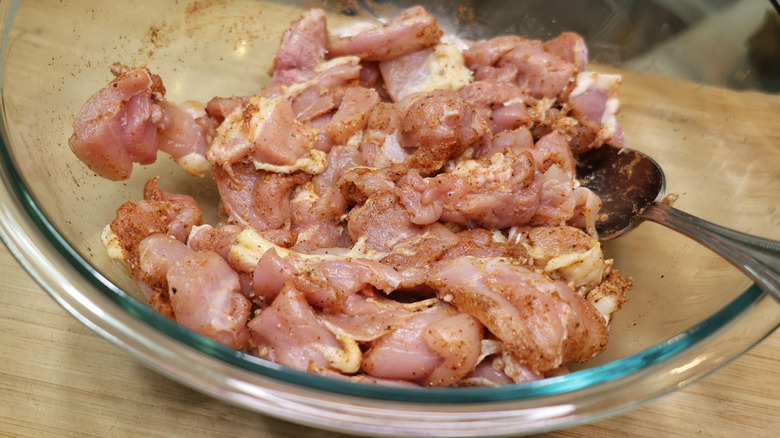bowl of cubed chicken thighs coated in spices
