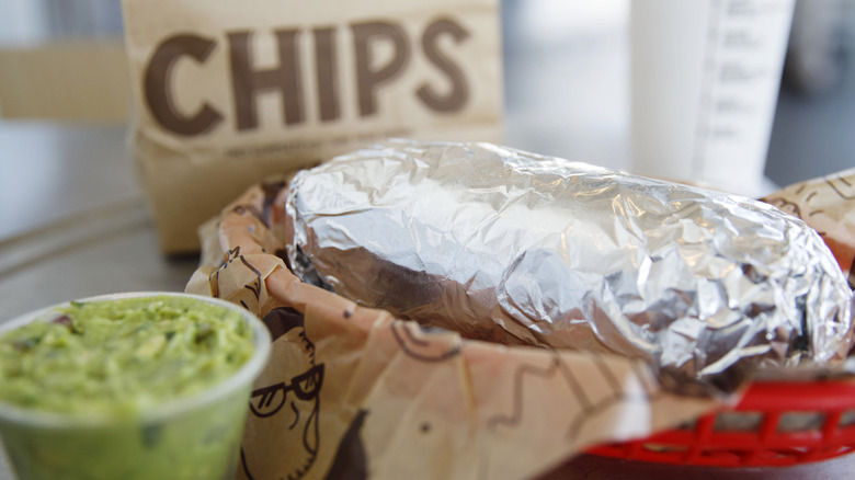 A Chipotle burrito with a side of chips and guacamole