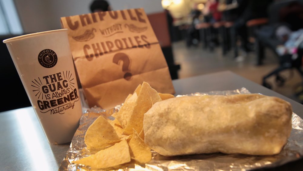 A Chipotle burrito with chips and a drink