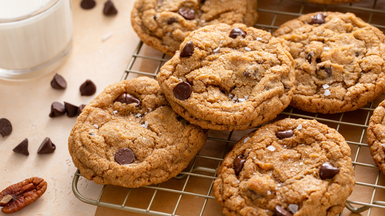 Chocolate chip cookies on a rack next to glass of milk