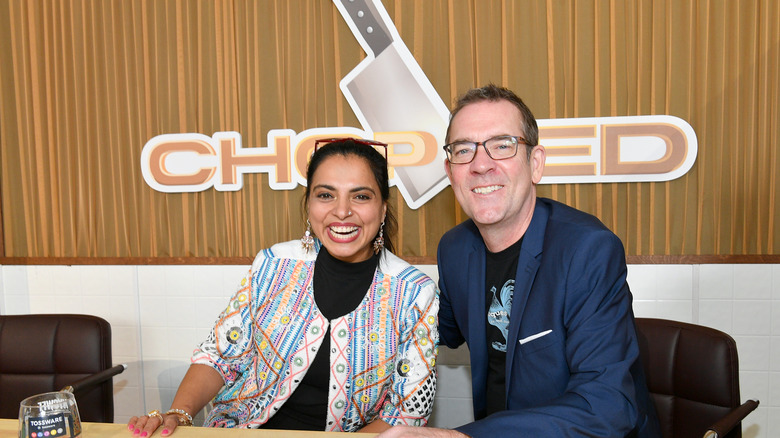 Maneet Chauhan and Ted Allen in front of Chopped logo